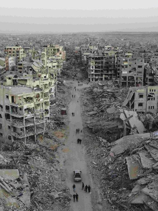 Luftbild der Zerstörung im Viertel Sheikh Ridwan in Gaza Stadt: Zerbombte Häuser, einige sind nur noch Schutt und Asche. Auf einer Straße laufen Menschen, die nach dem Waffenstillstandsabkommen unter schwierigsten Bedingungen überleben.
