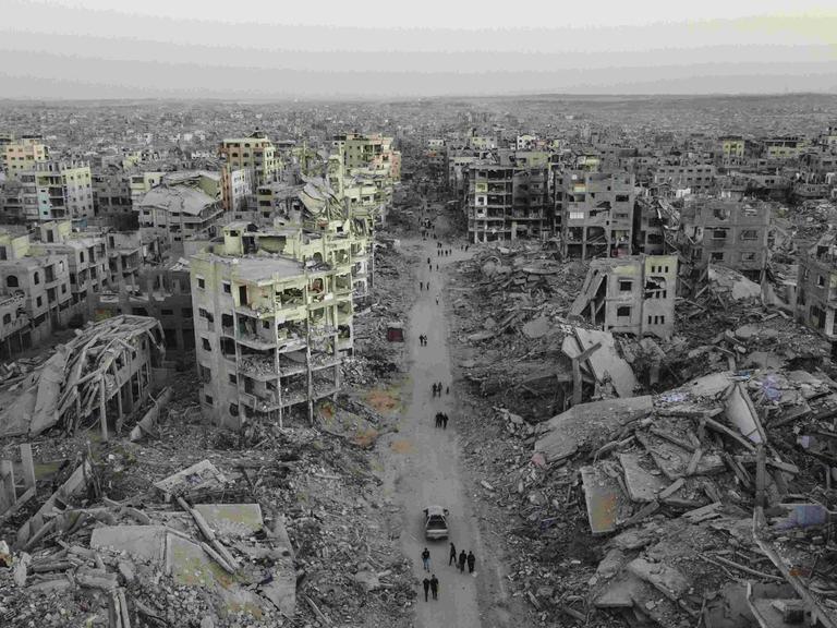 Luftbild der Zerstörung im Viertel Sheikh Ridwan in Gaza Stadt: Zerbombte Häuser, einige sind nur noch Schutt und Asche. Auf einer Straße laufen Menschen, die nach dem Waffenstillstandsabkommen unter schwierigsten Bedingungen überleben. Luftbild der Zerstörung im Viertel Sheikh Ridwan in Gaza Stadt: Zerbombte Häuser, einige sind nur noch Schutt und Asche. Auf einer Straße laufen Menschen, die nach dem Waffenstillstandsabkommen unter schwierigsten Bedingungen überleben.