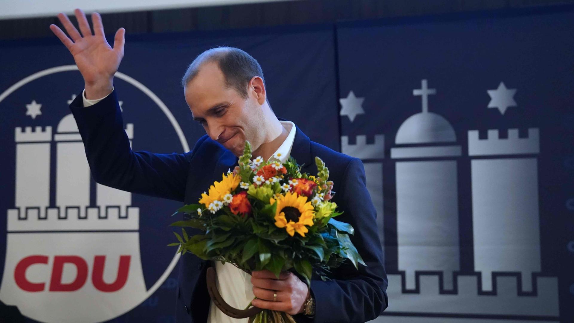 Das Foto zeigt den neuen Landesvorsitzenden der CDU, Dennis Thering, mit einem Blumenstrauß in der Hand.