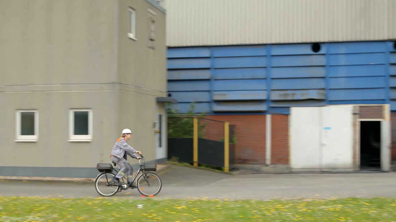 Stahlarbeiterin Kathi auf dem Fahrrad auf dem Weg zum Stahlwerk. Stahlarbeiterin Kathi auf dem Fahrrad auf dem Weg zum Stahlwerk.