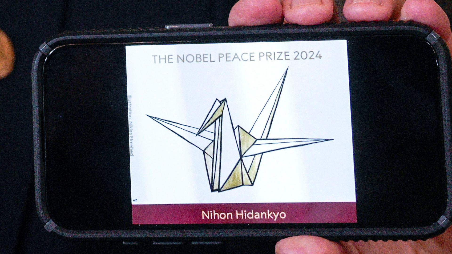 Oslo: Jorgen Watne Frydnes, der Vorsitzende des Nobelkomitees, präsentiert auf seinem Smartphone das Logo der japanischen Organisation Nihon Hidankyo. Oslo: Jorgen Watne Frydnes, der Vorsitzende des Nobelkomitees, präsentiert auf seinem Smartphone das Logo der japanischen Organisation Nihon Hidankyo.