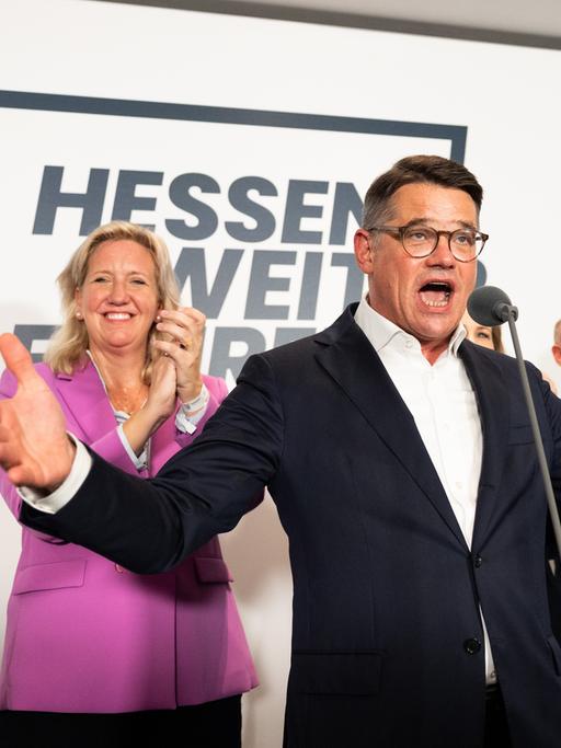 Boris Rhein (CDU), ein Mann Anfang 50, steht auf einer Bühne und breitet die Arme weit aus. Links hinter ihm steht eine Frau, Astrid Wallmann und Manfred Pentz. 