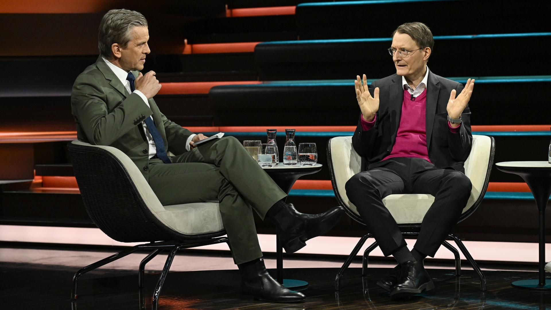 Karl Lauterbach (r.) sitzt dem Moderator Markus Lanz (l.) im Fernsehstudio gegenüber und spricht. Karl Lauterbach (r.) sitzt dem Moderator Markus Lanz (l.) im Fernsehstudio gegenüber und spricht.