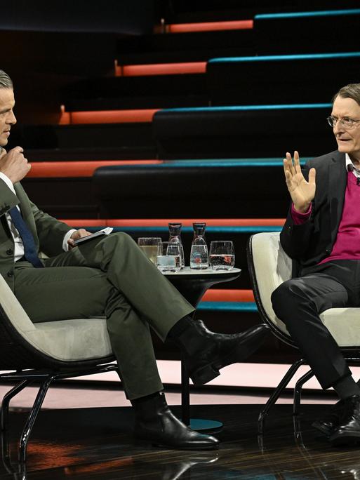 Karl Lauterbach (r.) sitzt dem Moderator Markus Lanz (l.) im Fernsehstudio gegenüber und spricht.