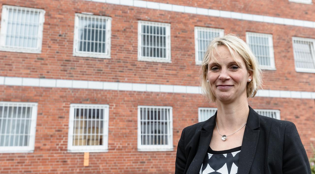Eine blonde Frau in schwarzem Blazer steht vor eine Kachelsteinwand: Leiterin der Justizvollzugsanstalt Neumünster, Yvonne Radetzki.