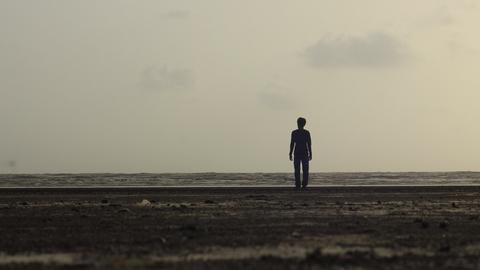 Eine Silhouette am Strand vor dem Meer.