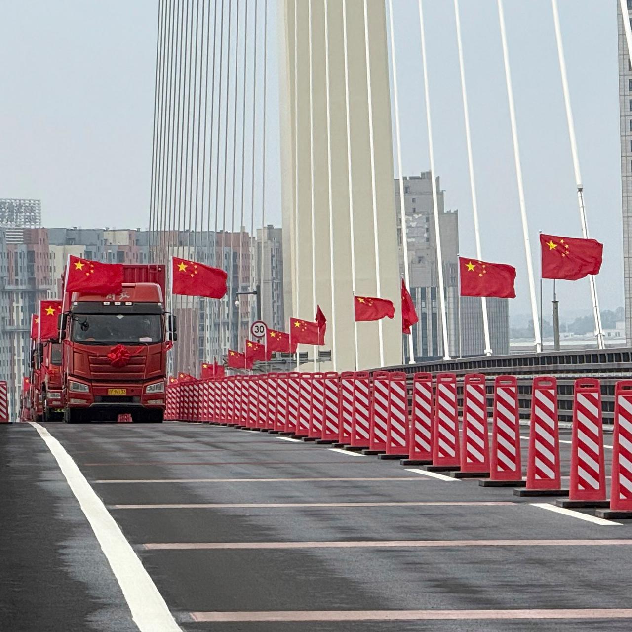 Lastwagen mit chinesischen Flaggen fahren während der Eröffnungsfeier über die neue chinesisch-nordkoreanische Yalu-Brücke.