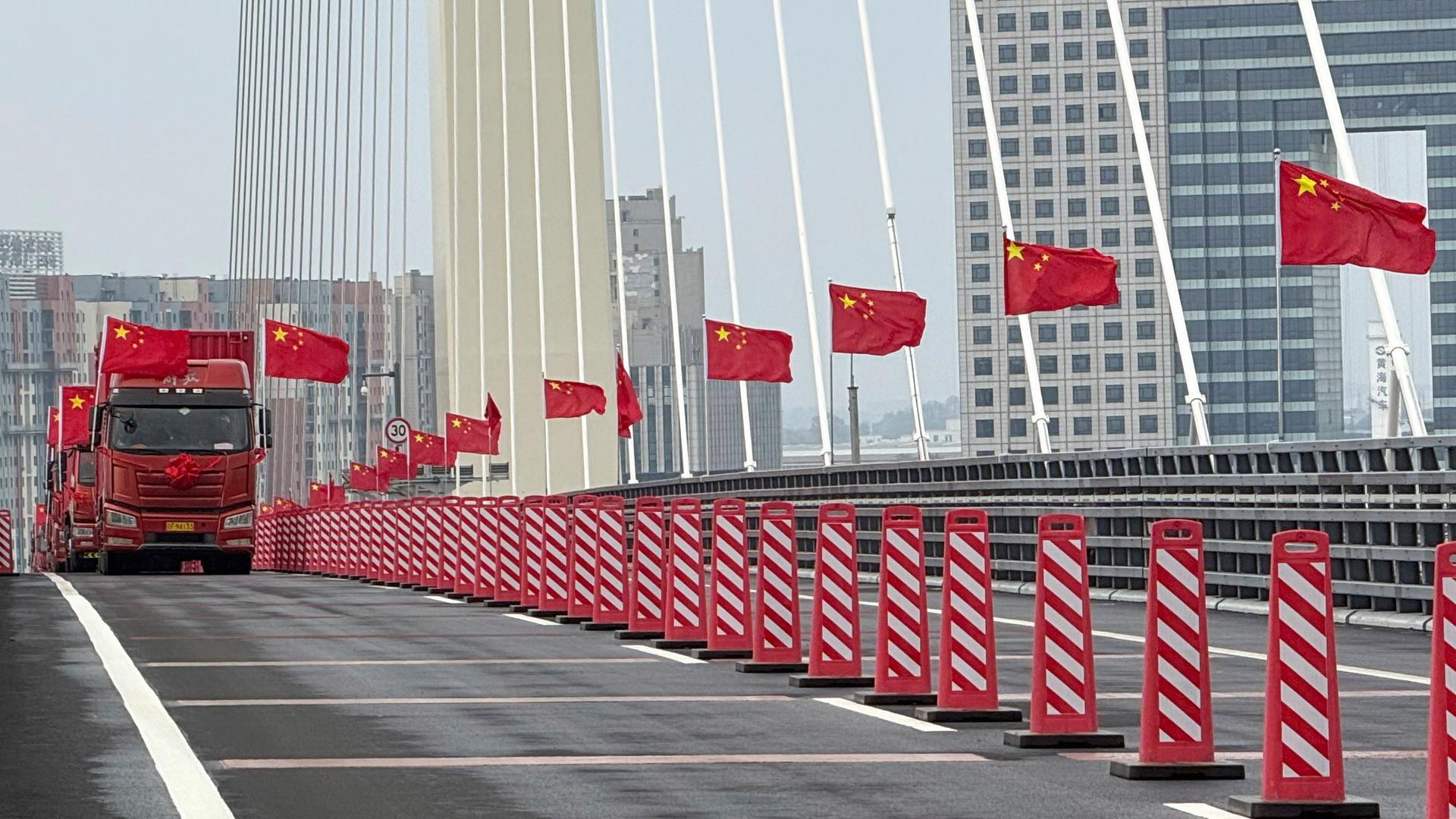 Lastwagen mit chinesischen Flaggen fahren während der Eröffnungsfeier über die neue chinesisch-nordkoreanische Yalu-Brücke.