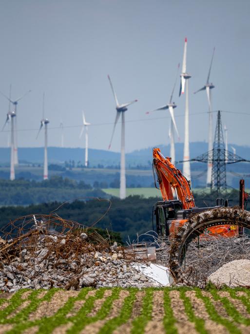 Windpark nördlich von Marsberg, alte Windenergieanlage wird abgerissen. Beton, Stahl und andere Materialien liegen vor einem roten Bagger. Im Hintergrund sind weitere Windräder zu sehen.