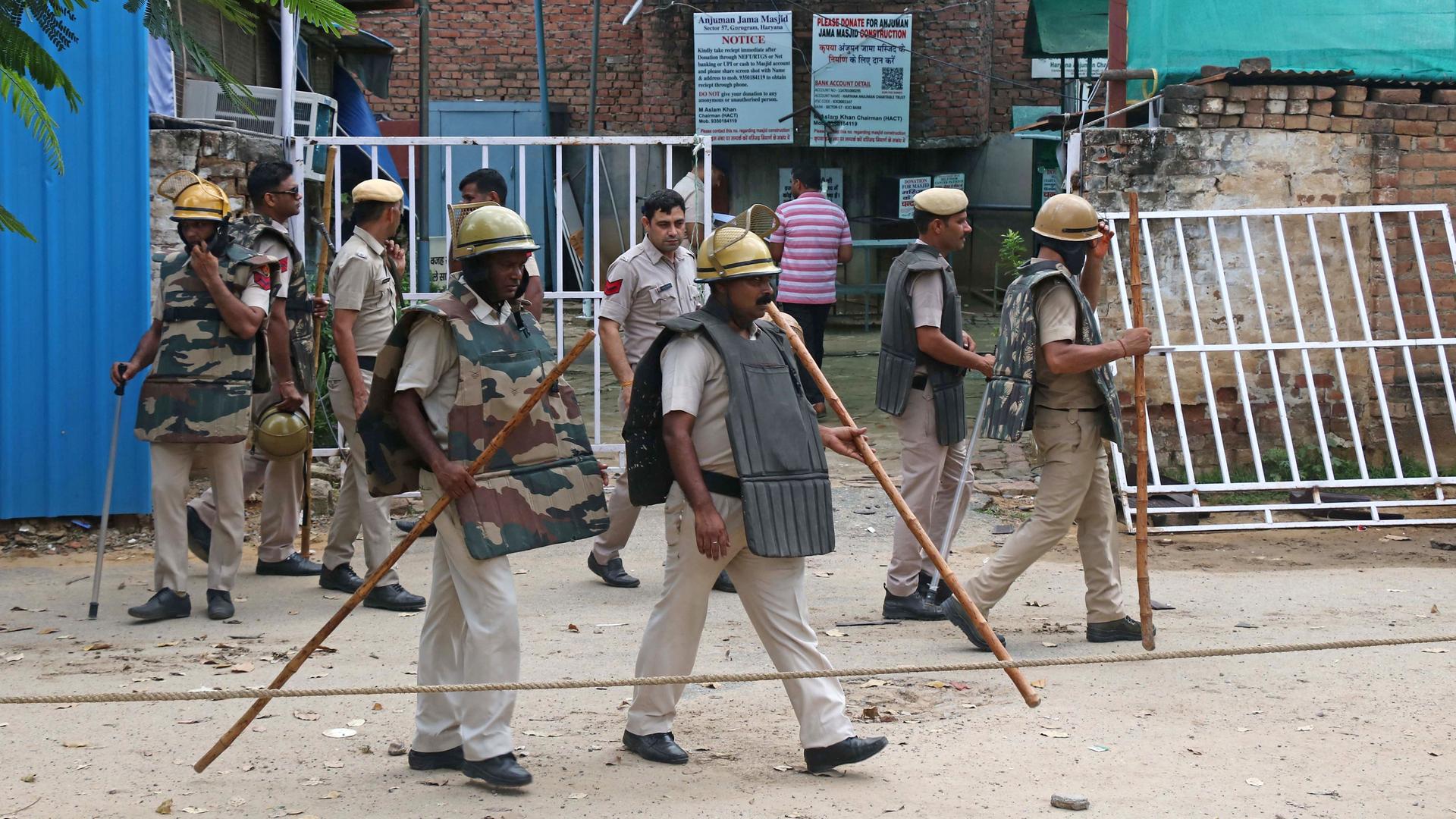 Indische Polizisten stehen vor einem Gebäude, in dem es religiöse Auseinandersetzungen gegeben hat.