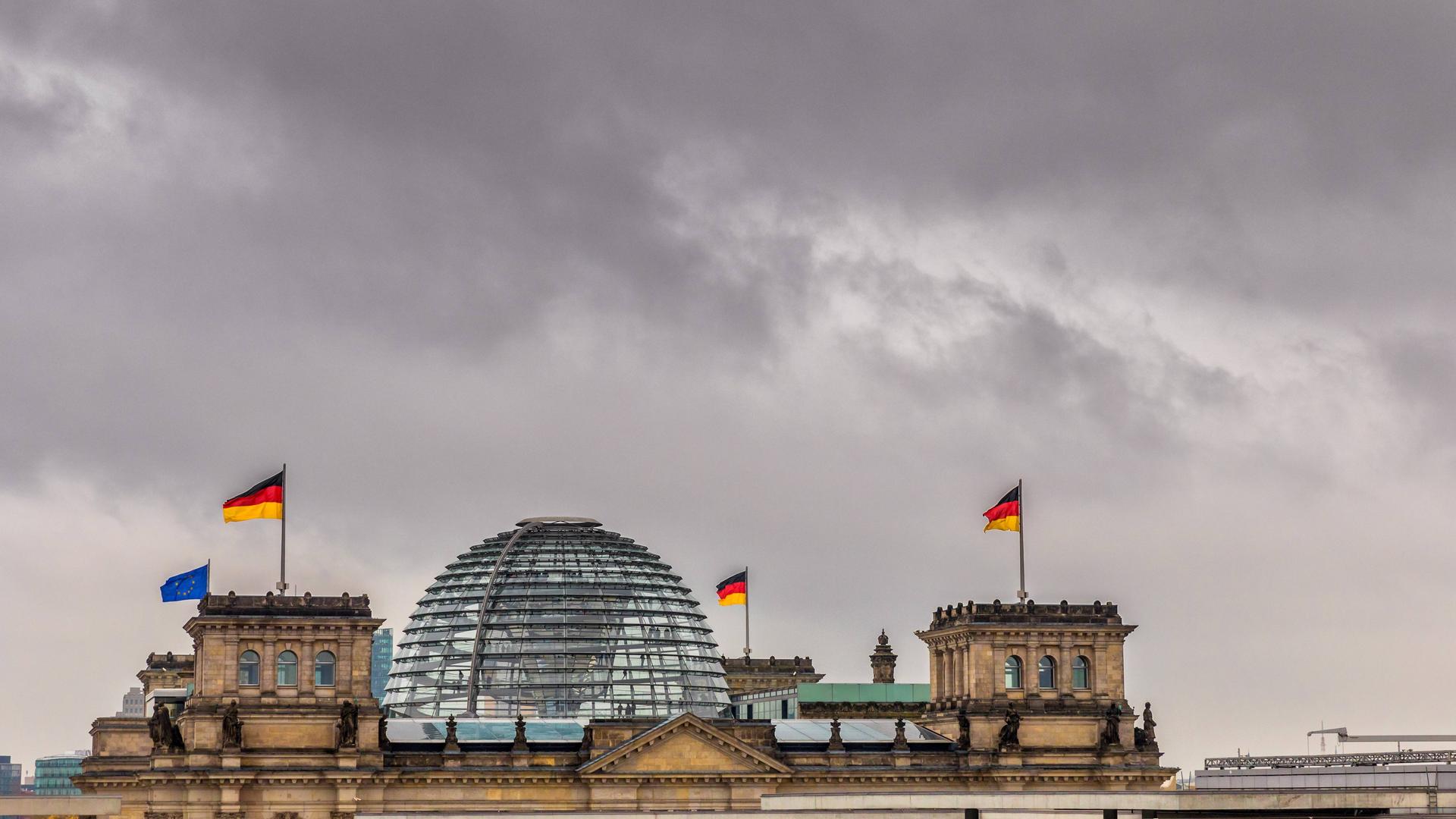 Dunkle Wolken über der gläsernen Kuppel des Reichstagsgebäudes in Berlin.
