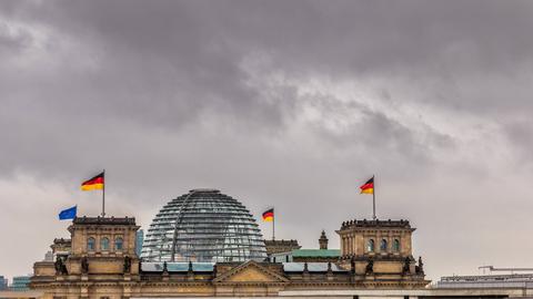 Dunkle Wolken über der gläsernen Kuppel des Reichstagsgebäudes in Berlin
