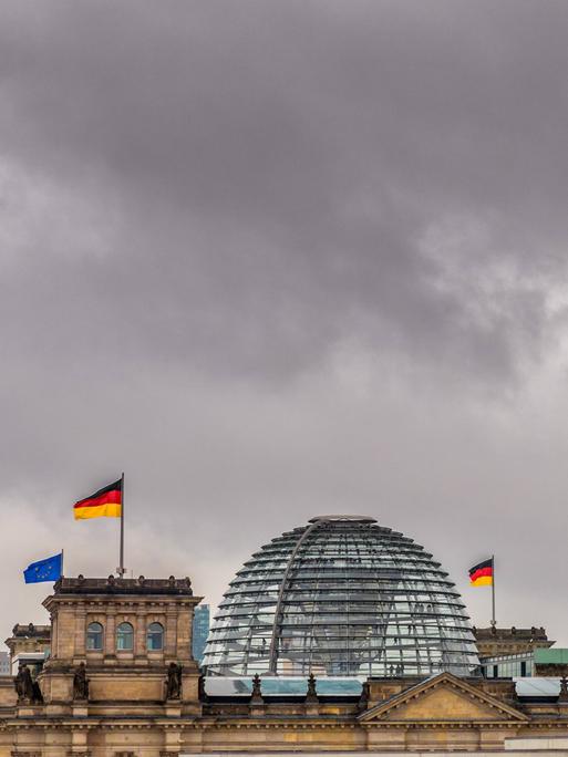 Dunkle Wolken über der gläsernen Kuppel des Reichstagsgebäudes in Berlin