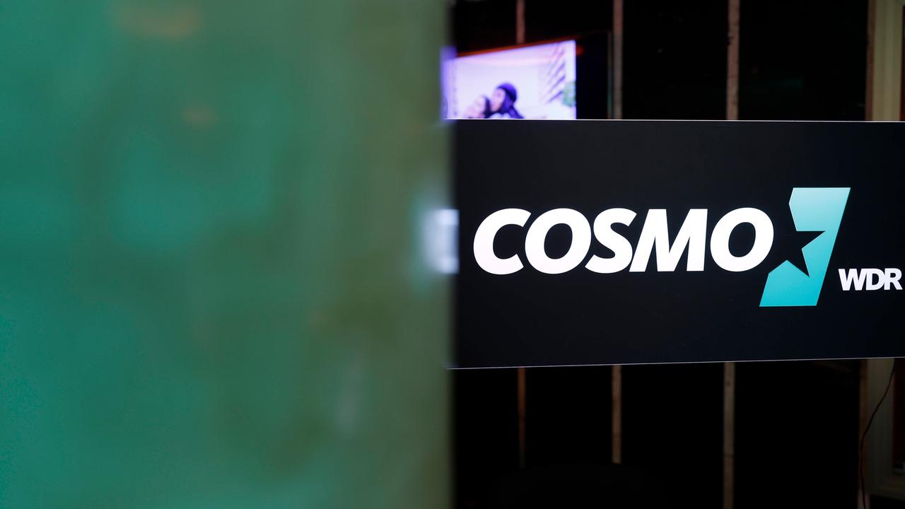 Das Logo des Hörfunksenders Cosmo an der Scheibe eines Studios. 