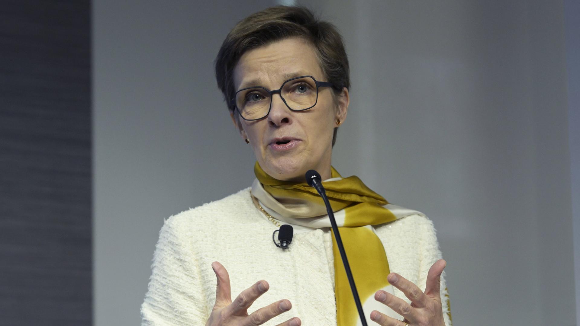 EZB-Bankenaufsichtschefin Claudia Buch steht vor einem Mikrofon und gestikuliert mit beiden Händen.