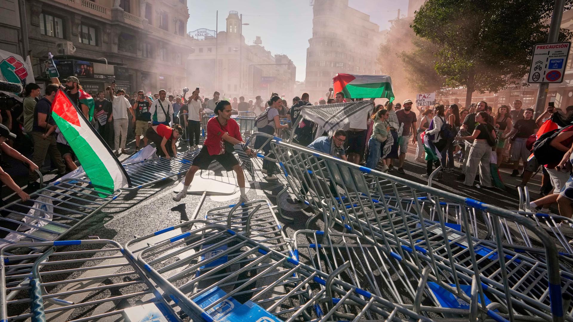 Ein Demonstrant kippt Absperrungen um. Ein Demonstrant kippt Absperrungen um.