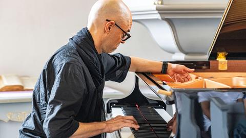 Nik Bärtsch spielt solo auf der Muziekbiennale Niederrhein 2022 auf Schloss Diersfordt in Wesel. Er sitzt schwarzgekleidet vor einem Flügel.