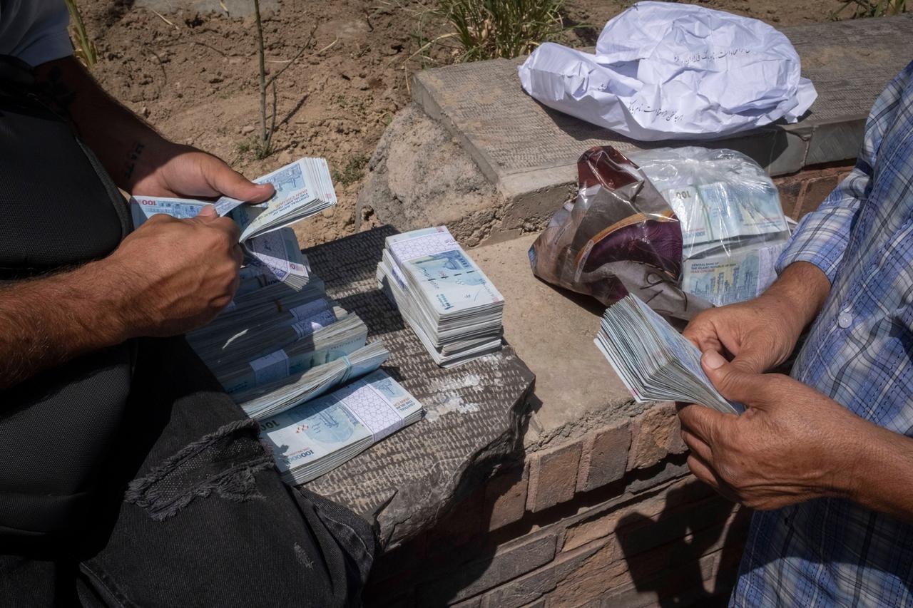 Iranische Straßenwechselstuben. Zwei Männer zählen Geldbündel.