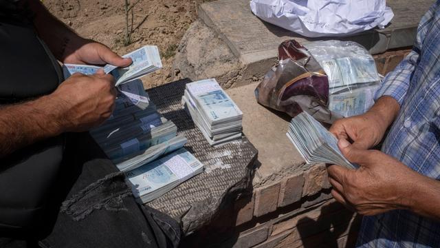 Iranische Straßenwechselstuben. Zwei Männer zählen Geldbündel.