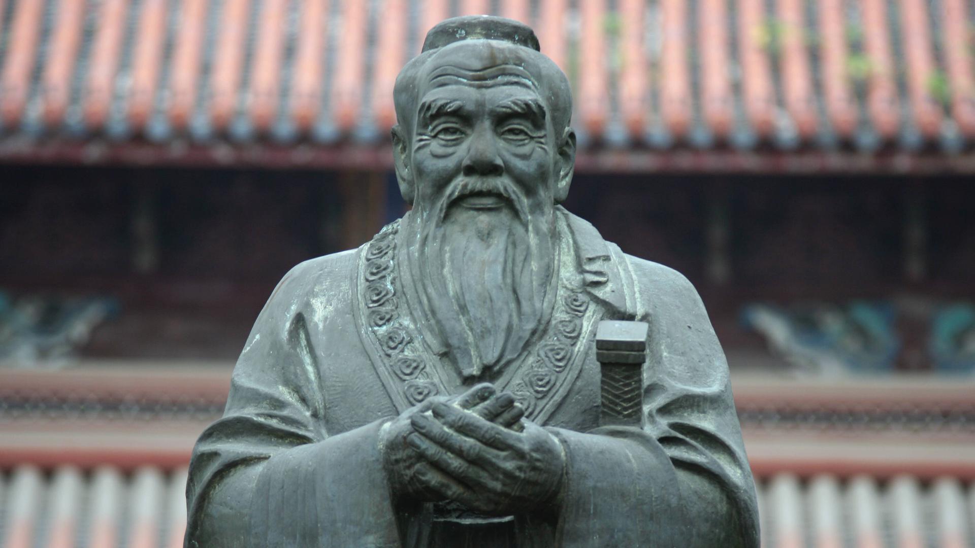 Frontalansicht einer Steinskulptur des chinesischen Philosophen Konfuzius, der einen mit gütiger Miene anblickt. Frontalansicht einer Steinskulptur des chinesischen Philosophen Konfuzius, der einen mit gütiger Miene anblickt.