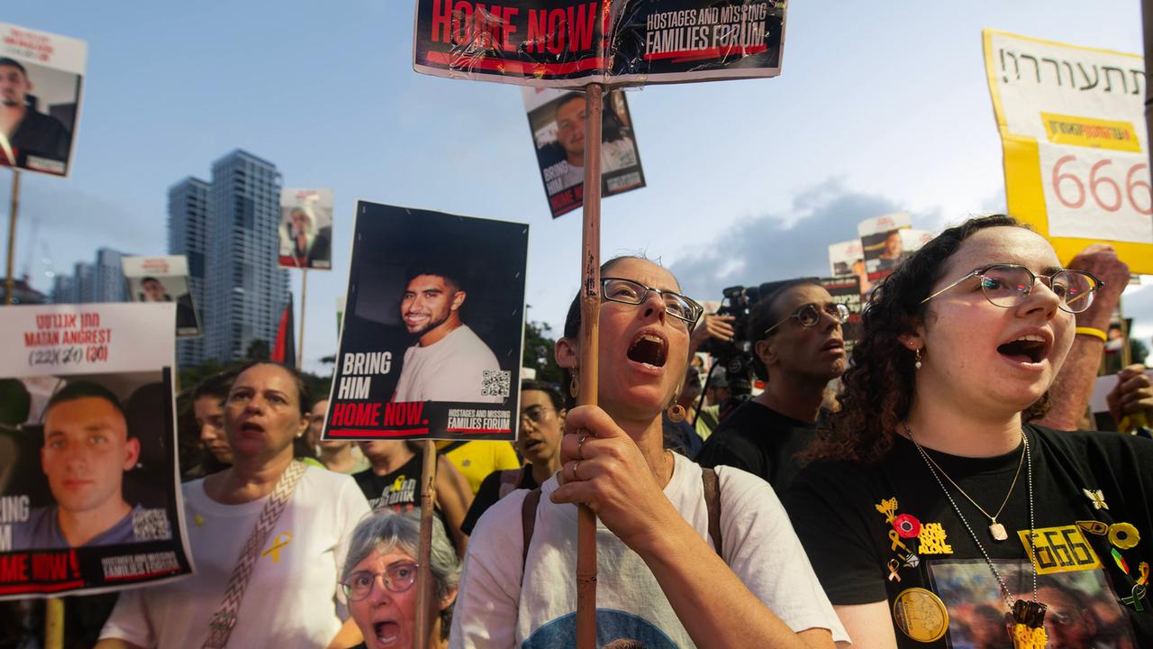 Protestierende in einer Menschenmenge tragen Bilder von Entführten auf Schildern und auf ihren T-Shirts.