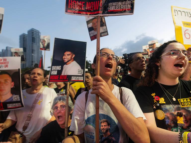 Protestierende in einer Menschenmenge tragen Bilder von Entführten auf Schildern und auf ihren T-Shirts.
