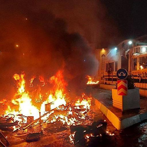 Hell loderndes Feuer vor einem weißen Gebäude. 