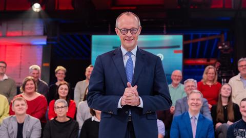 Bundeskanzler Friedrich Merz (CDU) steht vor der Live-Sendung der ARD-"Arena" in der Lemo Kulturhalle. Im Hintergrund sitzen Zuschauerinnen und Zuschauer.