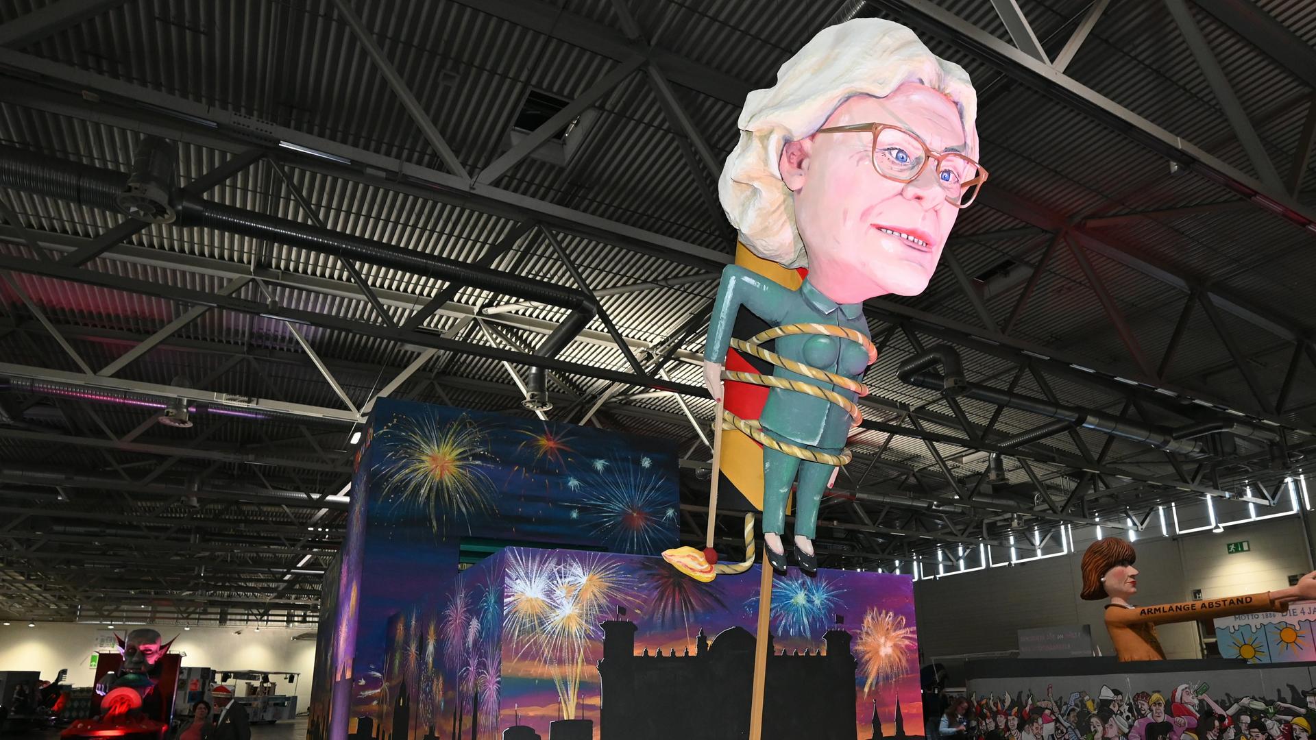 Ein Motivwagen Christine Lambrecht und Silvester steht beim Richtfest des Kölner Rosenmontagszug 2023 in einer Halle. Ein Motivwagen Christine Lambrecht und Silvester steht beim Richtfest des Kölner Rosenmontagszug 2023 in einer Halle.