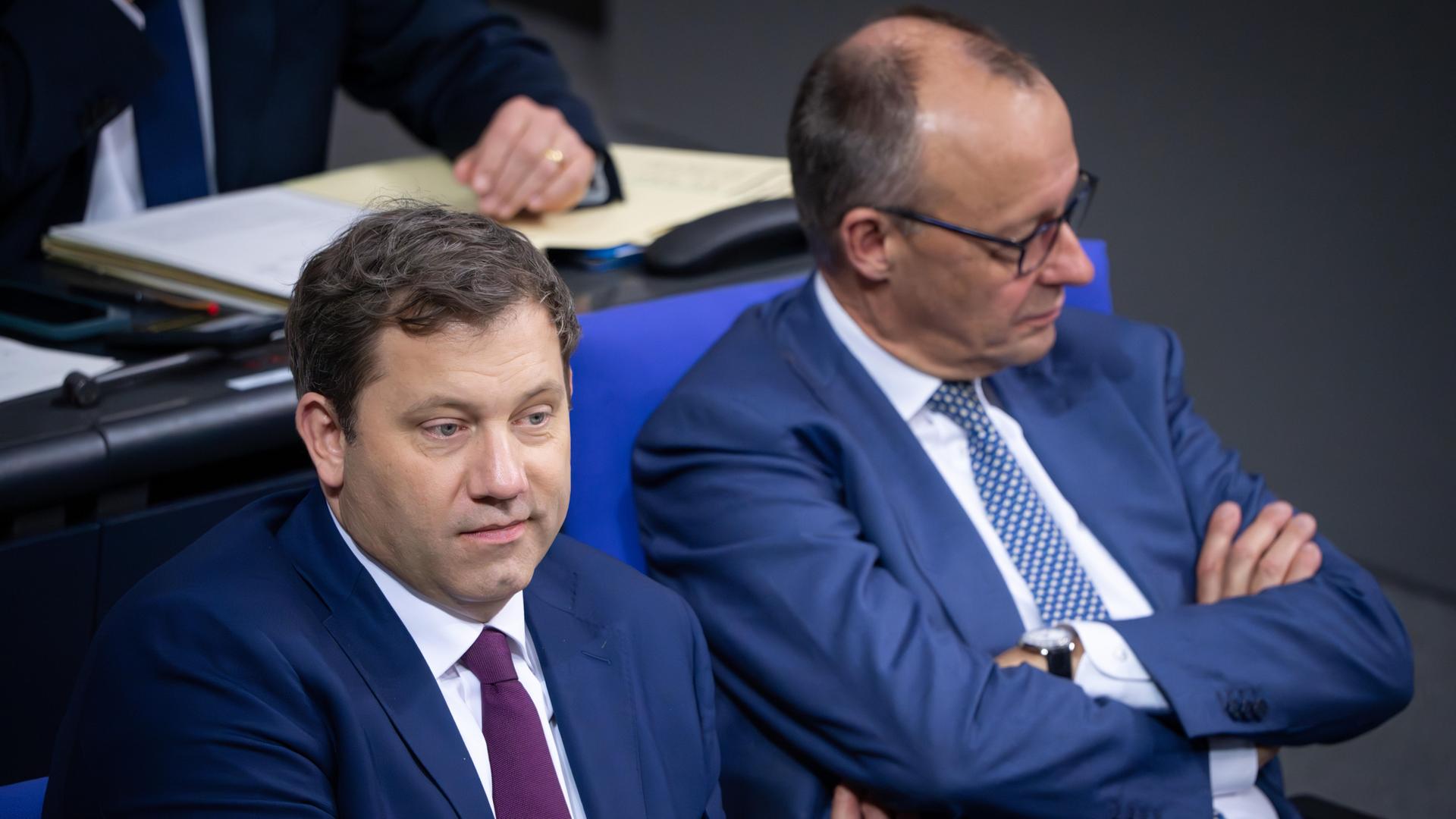Lars Klingbeil und Friedrich Merz sitzen nebeneinander auf der Regierungsbank im Deutschen Bundestag und blicken in unterschiedliche Richtungen.