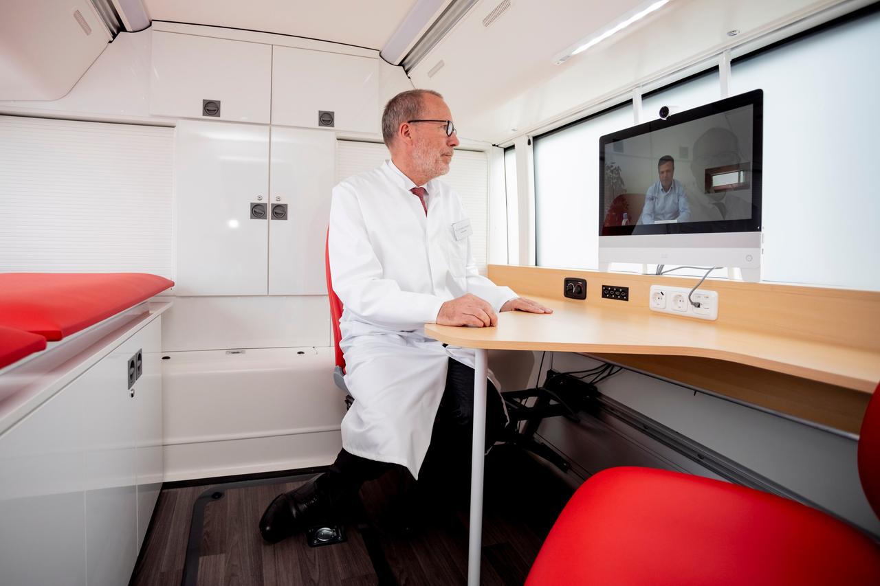 Ein leitender Arzt der Deutschen Bahn, unterhält sich bei einem Pressetermin zur mobilen Arztpraxis "Medibus" im Sprechzimmer eines Busses über ein System zur Telemedizin miteinem Mann.