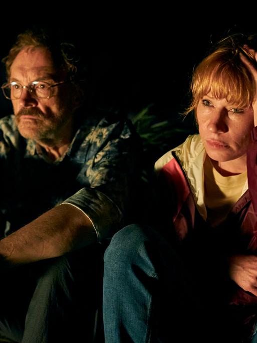 Josef Hader und Birgit Minichmayr sitzen in einer Szene  des Films  "Andrea lässt sich scheiden" in der Dunkelheit nebeneinander..