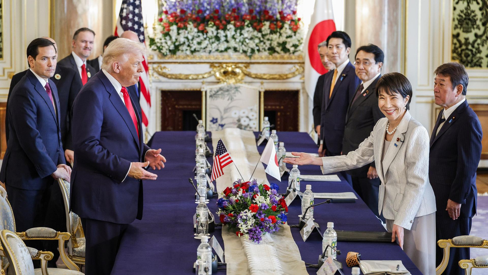 US-Präsident Donald Trump und Japans Premierministerin Sanae Takaichi stehen sich an einem Konferenztisch gegenüber. Im Hintergrund stehen auf beiden Seiten des Tischs weitere Teilnehmer des Gipfeltreffens. US-Präsident Donald Trump und Japans Premierministerin Sanae Takaichi stehen sich an einem Konferenztisch gegenüber. Im Hintergrund stehen auf beiden Seiten des Tischs weitere Teilnehmer des Gipfeltreffens.
