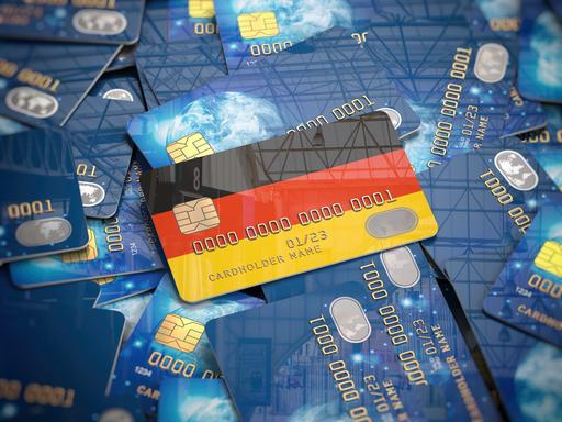 Illustration einer Kreditkarte mit den deutschen Nationalfarben, die auf einem Haufen anderer Kreditkarten liegt.