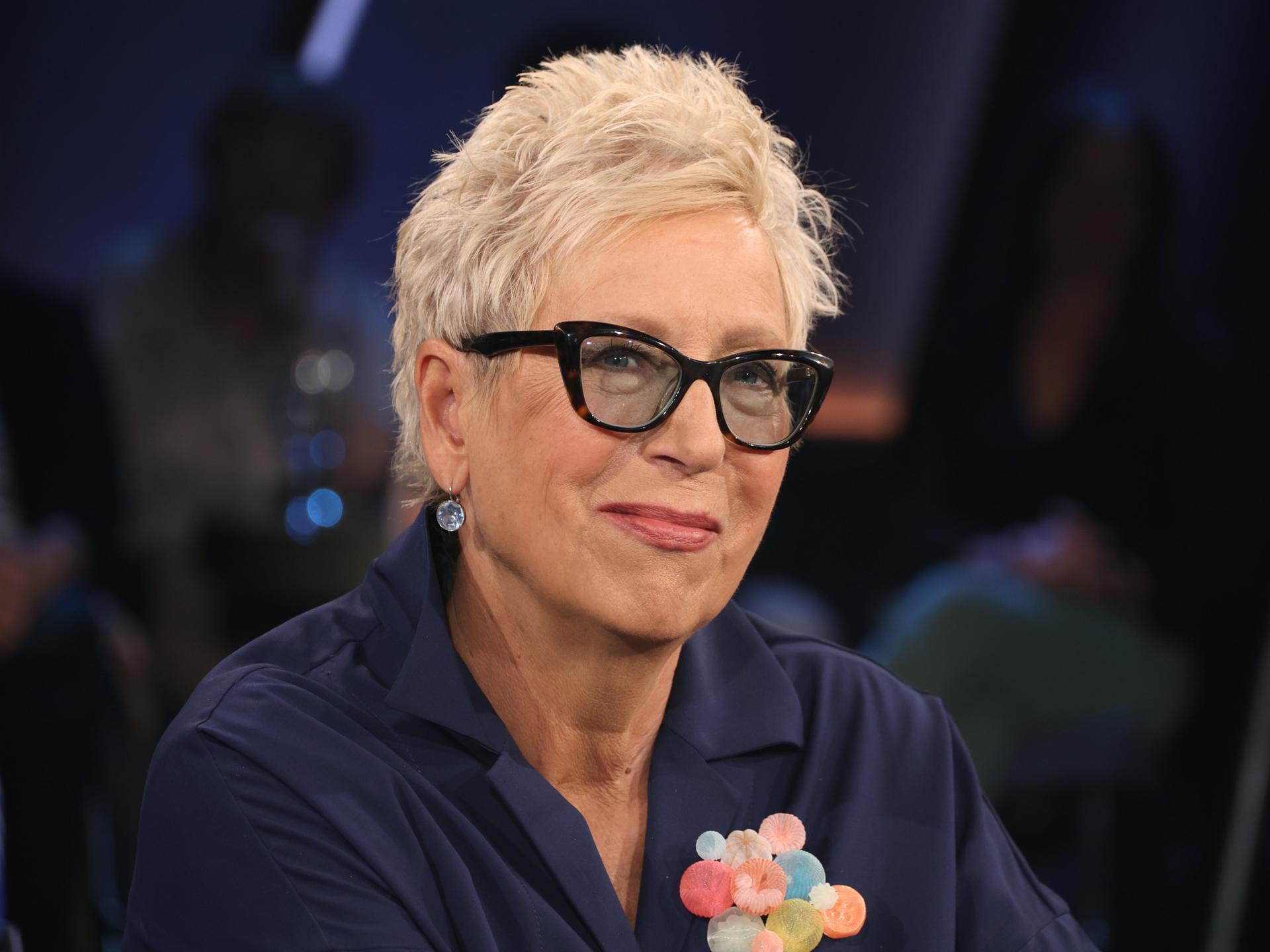 Eine Frau mit kurzen Haaren und Brille in einem Fernsehstudio