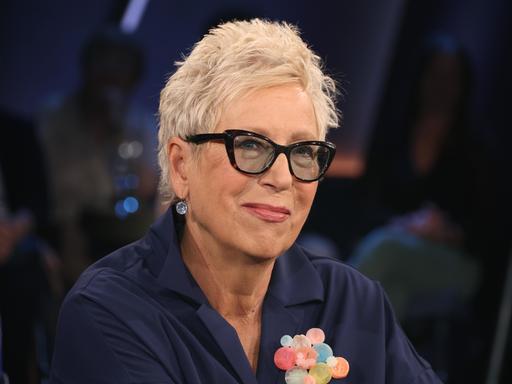 Eine Frau mit kurzen Haaren und Brille in einem Fernsehstudio