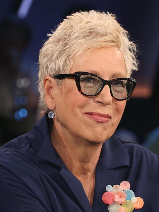 Eine Frau mit kurzen Haaren und Brille in einem Fernsehstudio