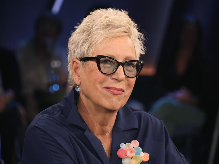 Eine Frau mit kurzen Haaren und Brille in einem Fernsehstudio