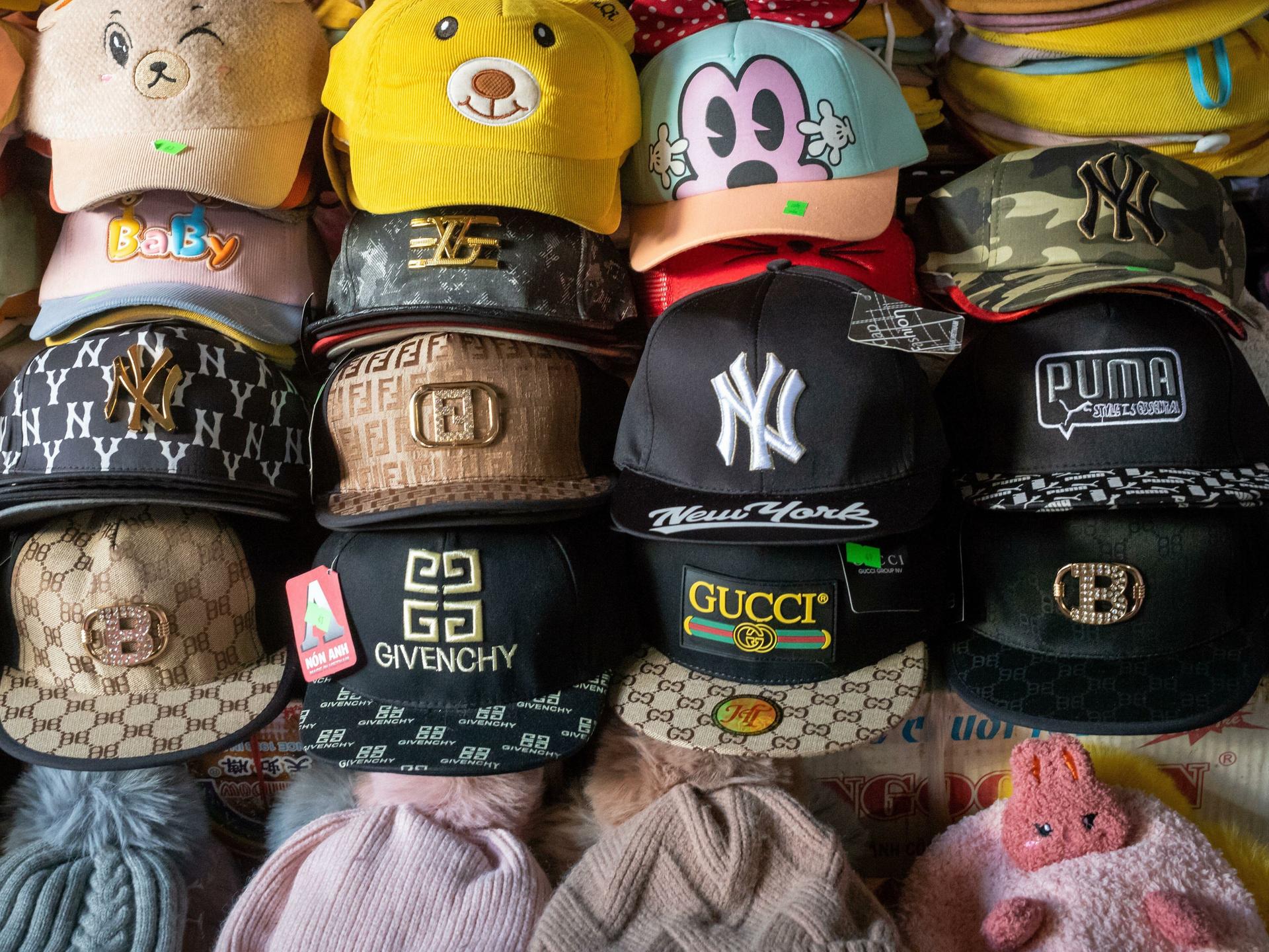 Eine Reihe von gefälschten Designer Caps in einer Markt-Auslage, in der Mitte eine 
Fake-Gucci-Kappe