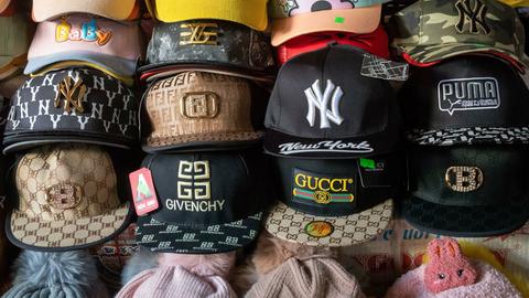 Eine Reihe von gefälschten Designer Caps in einer Markt-Auslage, in der Mitte eine 
Fake-Gucci-Kappe.