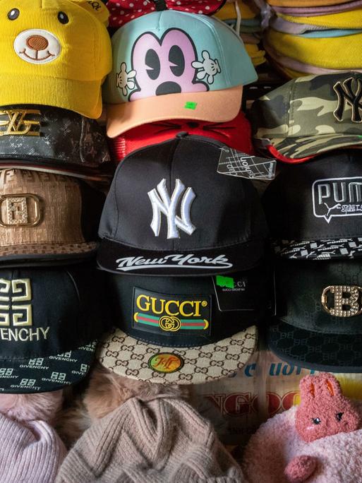 Eine Reihe von gefälschten Designer Caps in einer Markt-Auslage, in der Mitte eine
Fake-Gucci-Kappe Eine Reihe von gefälschten Designer Caps in einer Markt-Auslage, in der Mitte eine
Fake-Gucci-Kappe