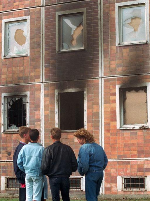 Blick auf das von über 100 Vietnamesen bewohnte Haus neben dem Asylbewerberheim, das am 24. August von Randalierern in Brand gesetzt wurde. Davor stehen Jugendliche. Die Scheiben sind zerstört, in dem Haus hat es gebrannt. (Archivfoto, 25.08.1992)