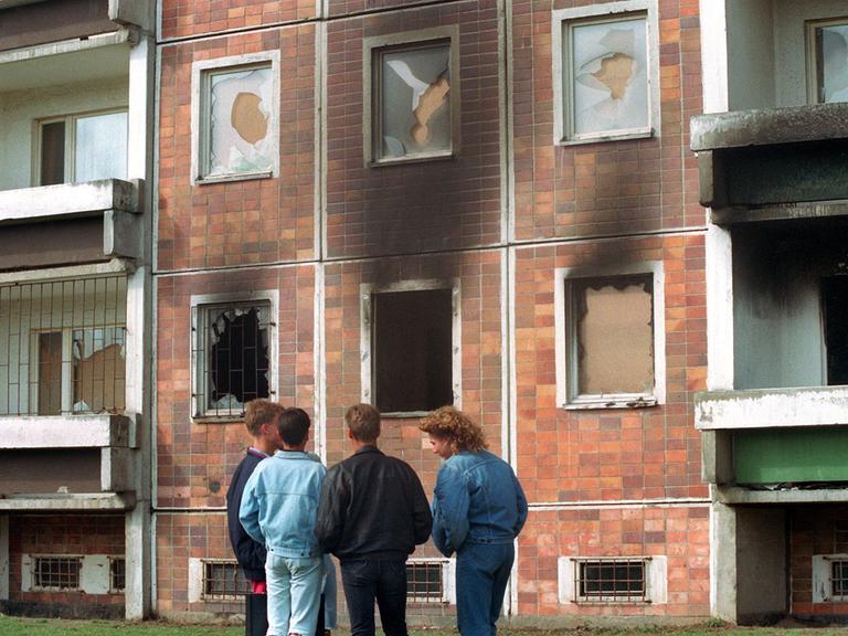 Blick auf das von über 100 Vietnamesen bewohnte Haus neben dem Asylbewerberheim, das am 24. August von Randalierern in Brand gesetzt wurde. Davor stehen Jugendliche. Die Scheiben sind zerstört, in dem Haus hat es gebrannt. (Archivfoto, 25.08.1992)