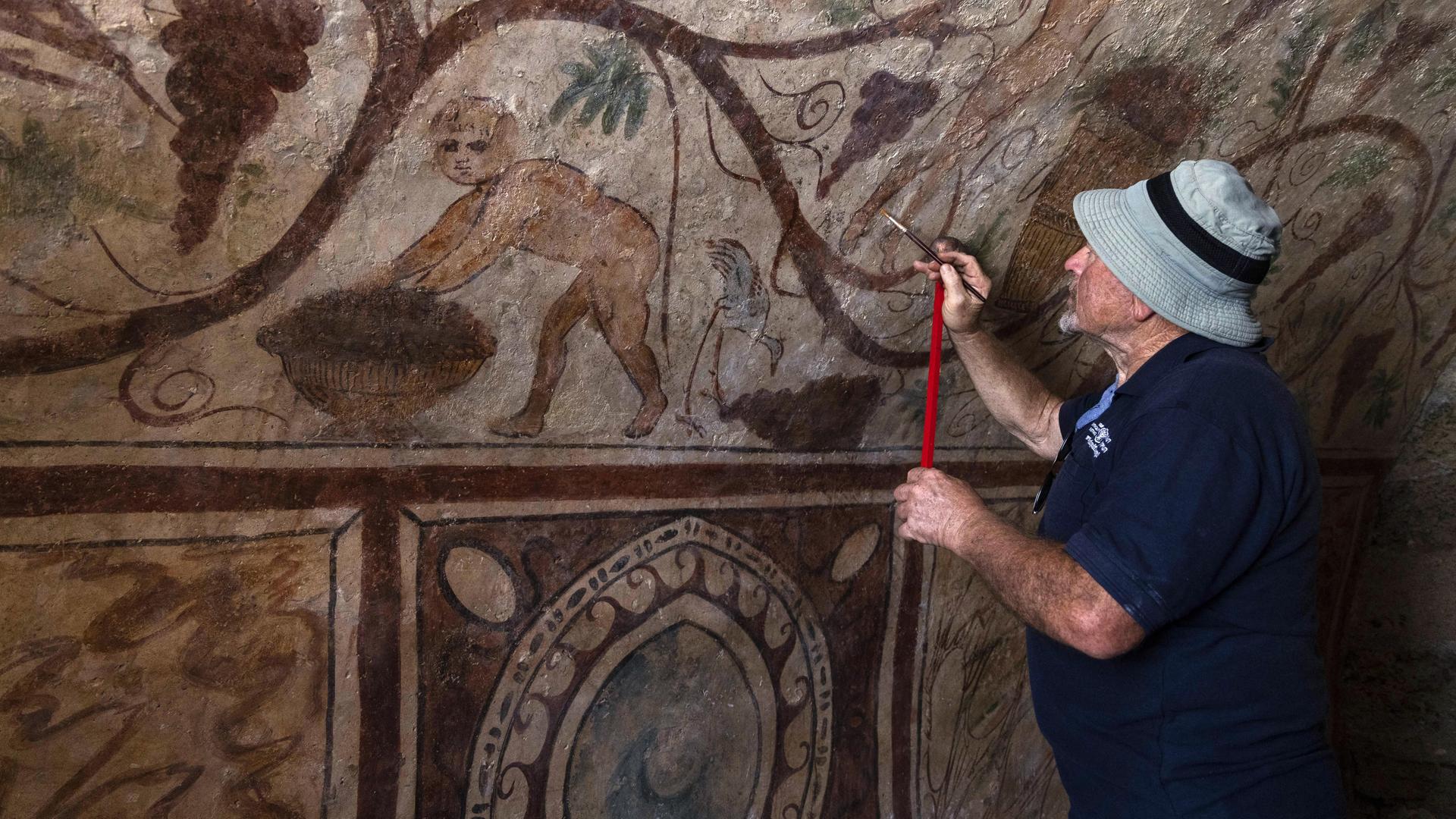 Ein Archäologe arbeitet an einer Wandbemalung. Ein Archäologe arbeitet an einer Wandbemalung.
