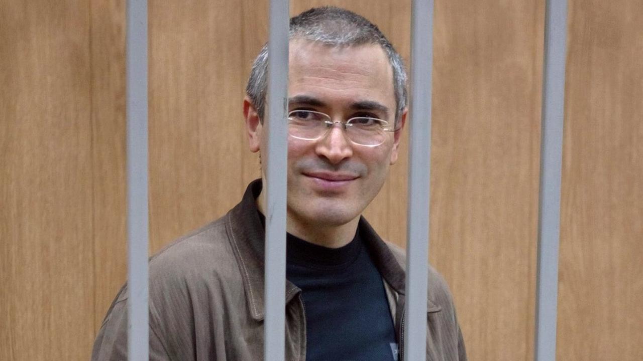 Der in Moskau angeklagte Geschäftsmann Michail Chodorkowski steht lächelnd hinter Gittern vor Gericht.