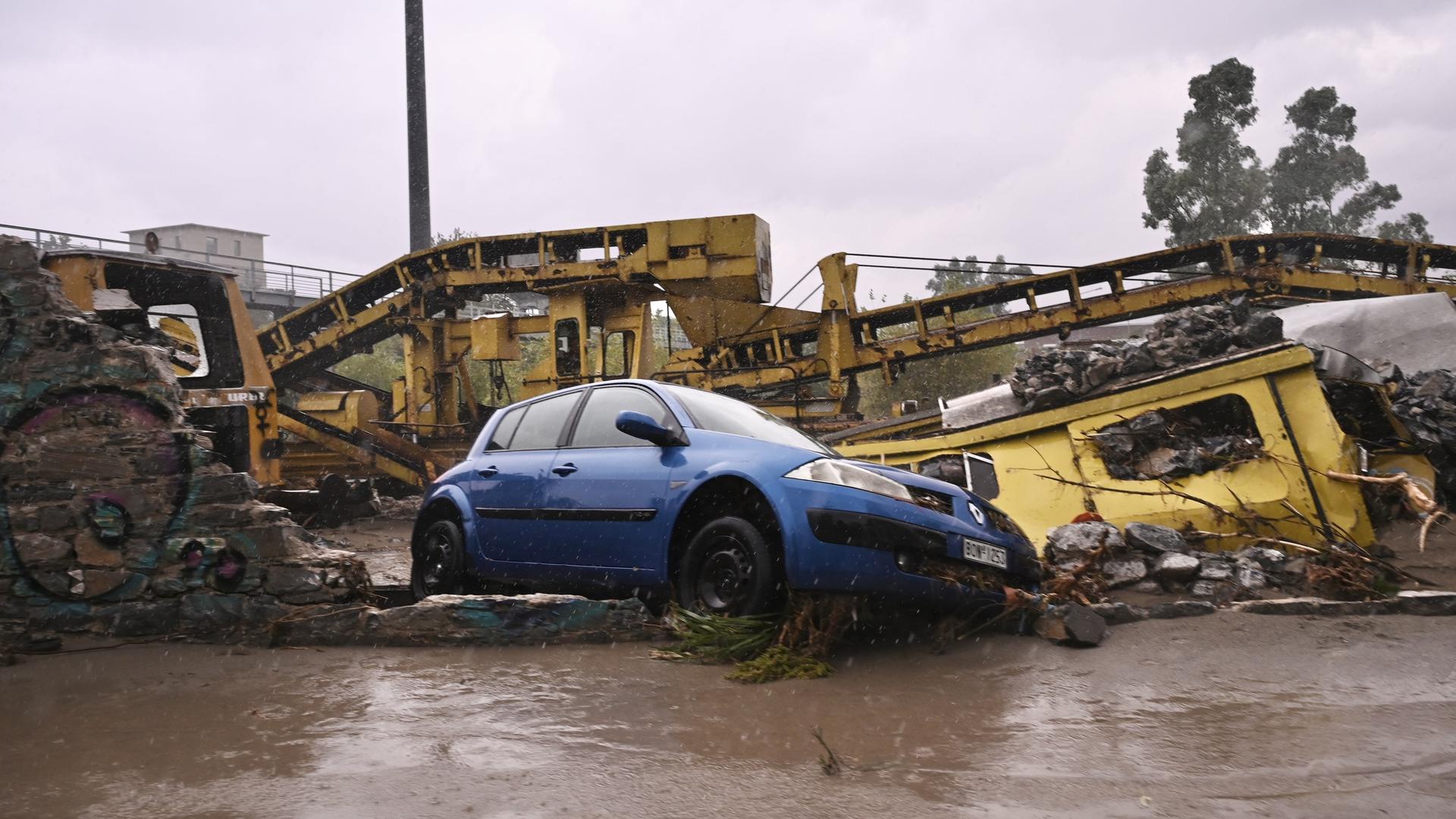 Das Foto zeigt ein beschädigtes Auto auf einer überfluteten Straße.
