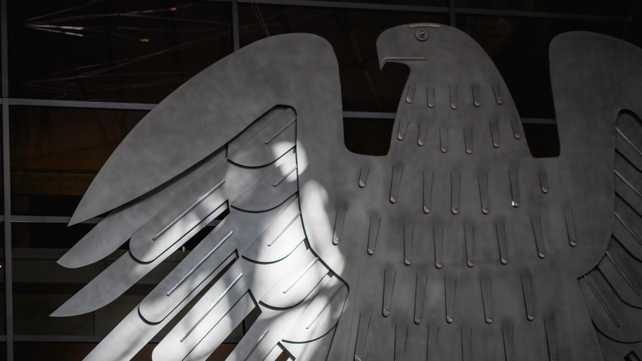 Der Bundesadler im Plenarsaal des Bundestags wird von der Sonne beschienen in Berlin.