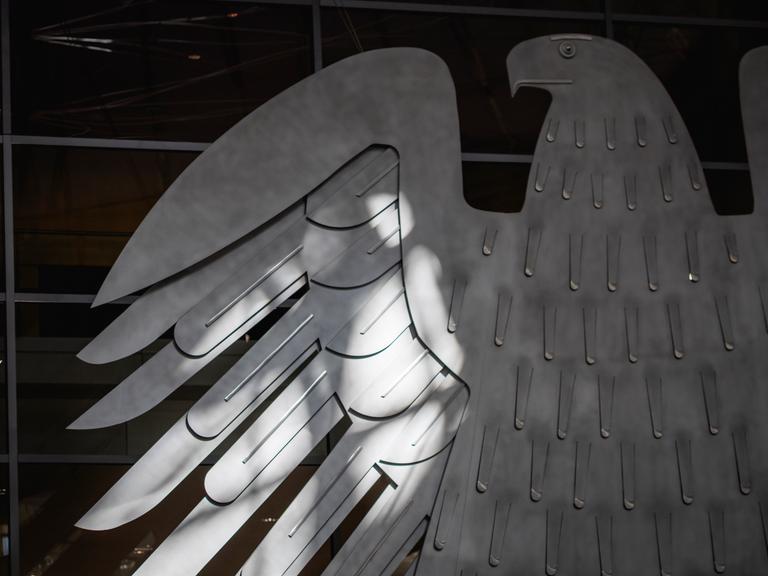 Der Bundesadler im Plenarsaal des Bundestags wird von der Sonne beschienen in Berlin.