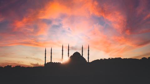 Die Türme und Kuppel der Hagia Sophia erscheinen im Gegenlicht als Schattenbilder, während der Himmel wild orange gefärbt ist.