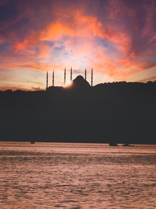 Die Türme und Kuppel der Hagia Sophia erscheinen im Gegenlicht als Schattenbilder, während der Himmel wild orange gefärbt ist.